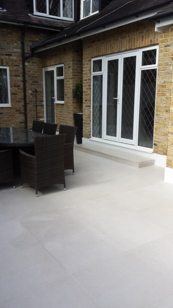 Pale paved patio and outdoor seating beside glazed garden doors