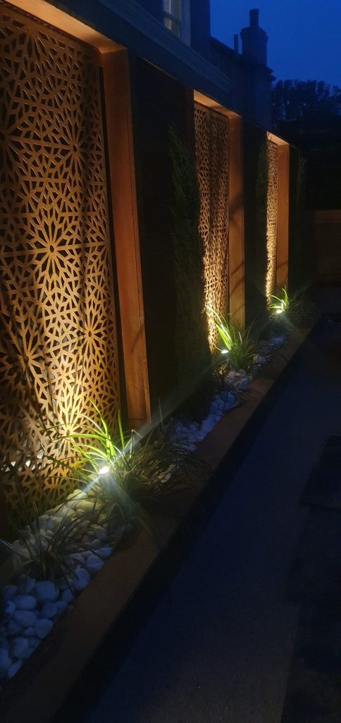 Split decorative garden panels beside a path at dusk.