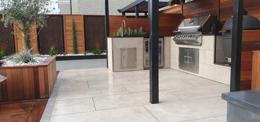 Garden design featuring a paved outdoor kitchen with a built-in barbecue, sink and raised planting beds