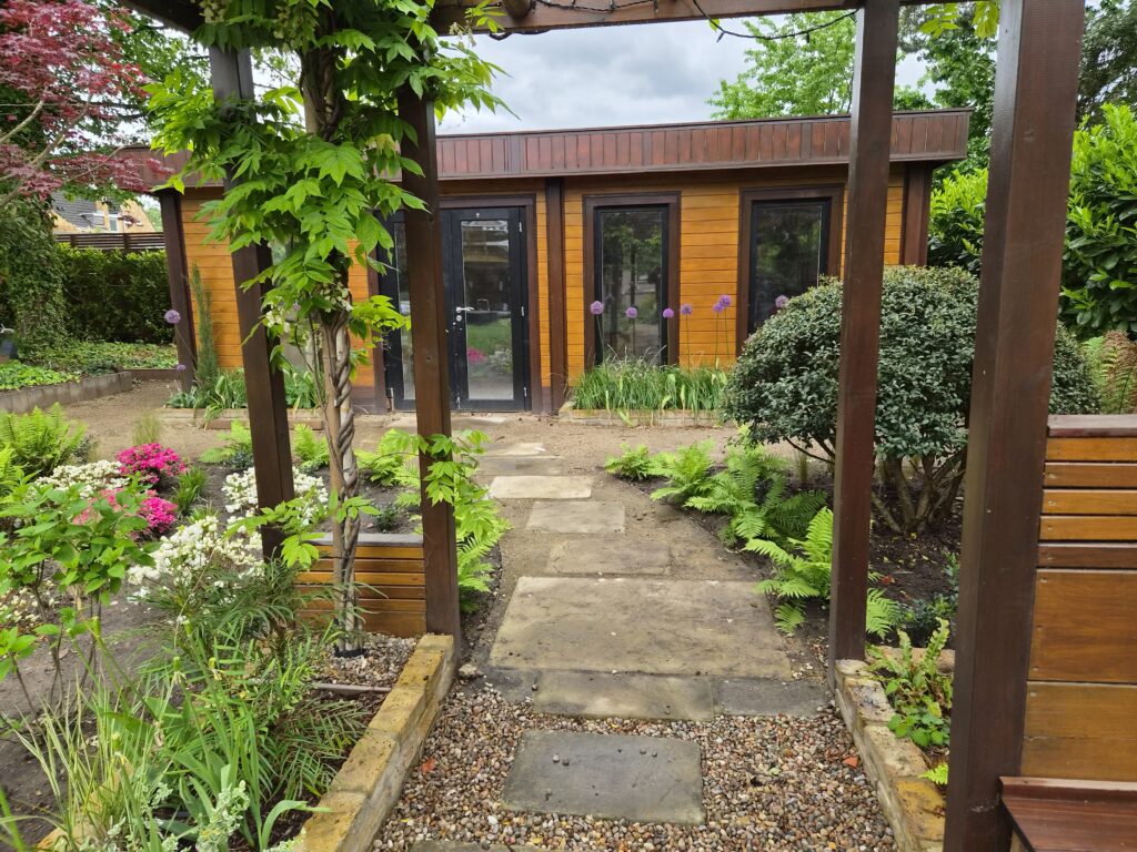 Mixed planting with ferns, azaleas and grasses beside a timber garden pergola