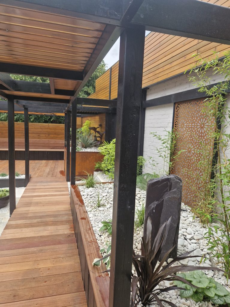 Cedar-clad garden room with allium planting and brick-edged beds
