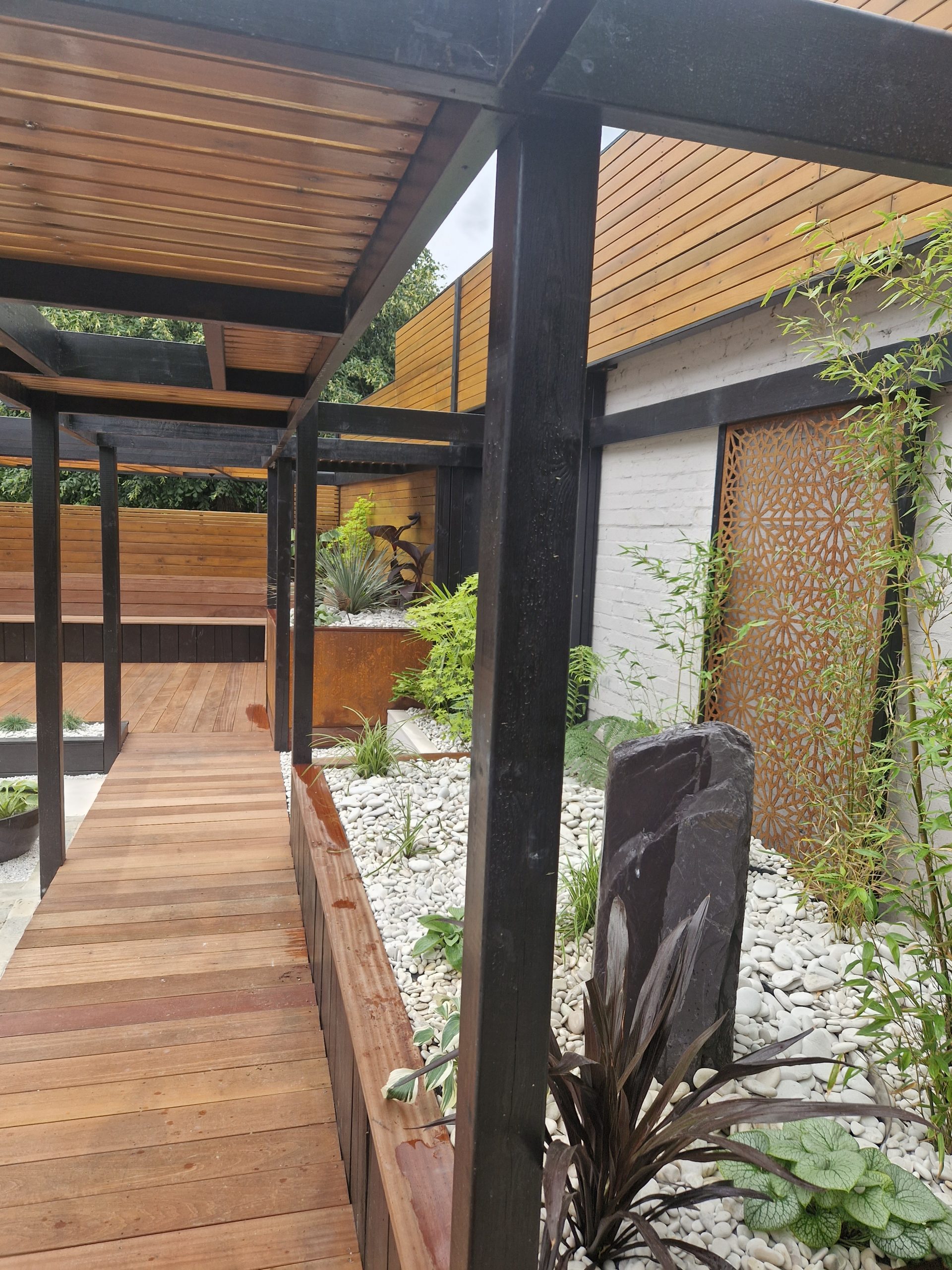 Cedar-clad garden room with allium planting and brick-edged beds