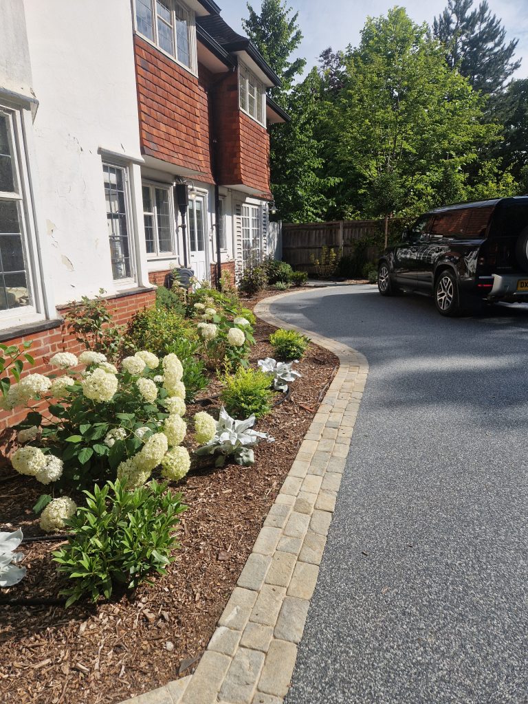 Curved driveway beside a planted border and house