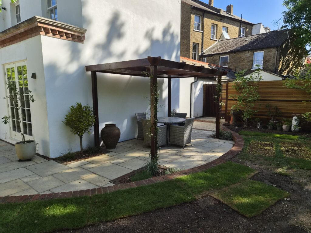 Dining pergola on limestone paving beside a white townhouse garden