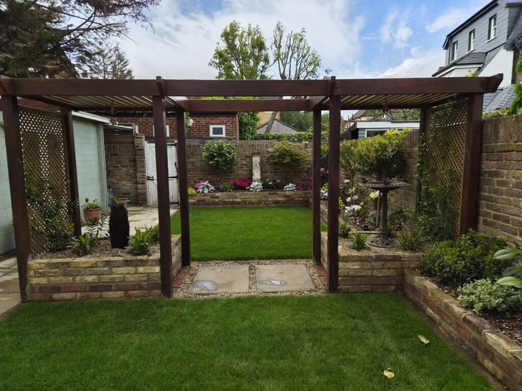 Timber pergola with brick-edged raised beds, fresh lawn and a bird bath